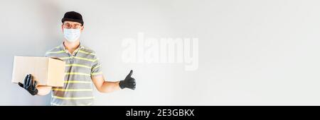 Delivery Service Mann in Schutzhandschuhe und Maske halten Karton-Box. Lieferservice, Online-Shopping und Logistikkonzept. Sichere Lieferung. Stockfoto