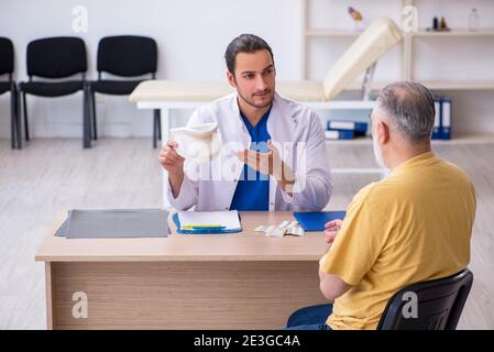 Alter Hals verletzten Mann besucht jungen Arzt Stockfoto