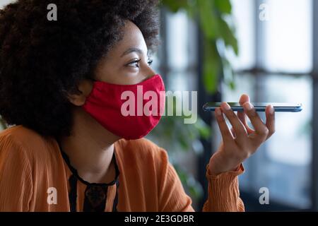 Gemischte Rasse Geschäftsfrau trägt Gesichtsmaske in kreativen Büro Stockfoto