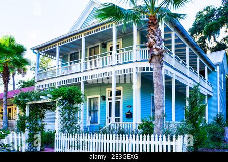 Ein zweistöckiges blaues Holzhaus mit Balkon und Veranda und Schaukelstühlen auf Amelia Island, in der historischen Innenstadt von Fernandina Beach, FL Stockfoto