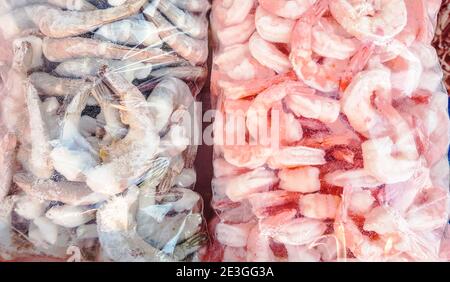 Zwei große Plastiktüten mit gefrorenen rohen und gekochten Garnelen, auf der Theke des Fischmarktes. Stockfoto