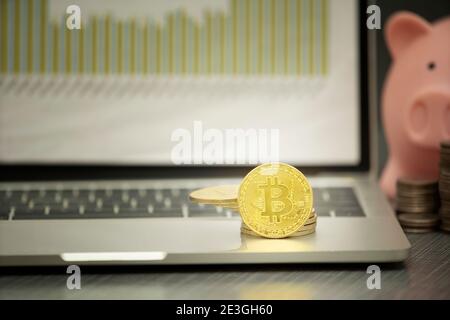 Bitcoin auf Laptop mit Chart Hintergrund, Investitionskonzept Stockfoto