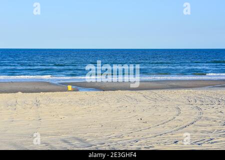 In einer kargen, leeren Strandszene blickt ein eineinziger gelber Strandstuhl auf den Atlantischen Ozean am Fernandina Beach, auf Amelia Island, FL, USA Stockfoto