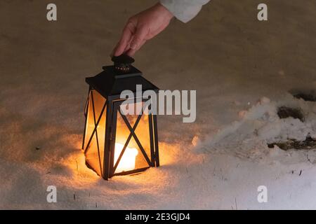 Frau, die eine Laterne in der Hand hält. Taschenlampe mit Kerzen im Schnee. Zugeschnittenes Foto. Konzept, Winter, Neujahr, weihnachten. Hochwertige Fotos Stockfoto