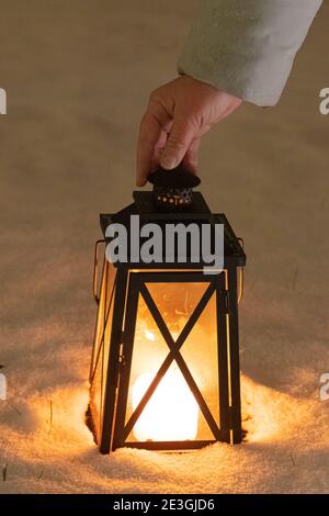 Frau, die eine Laterne in der Hand hält. Taschenlampe mit Kerzen im Schnee. Zugeschnittenes Foto. Konzept, Winter, Neujahr, weihnachten. Hochwertige Fotos Stockfoto