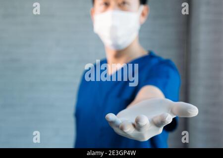 Männliche medizinische Arbeiter in Scrubs tragen Handschuhe und chirurgische Gesichtsmaske, geben Hände Unterstützung mit Kopieplatz bieten Stockfoto