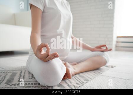 Ruhige schwangere Dame meditiert in Lotusposition auf dem Boden mit Teppich zu Hause sitzen. Stockfoto