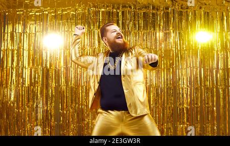 Glücklich junge Kerl in lustig glänzend goldenen Anzug tanzen und Spaß bei der Disco-Party Stockfoto