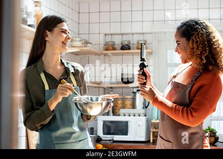 Glückliche zwei Freundinnen schießen Video mit Handy zu Online teilen, während Kochen in der Küche zu Hause Stockfoto