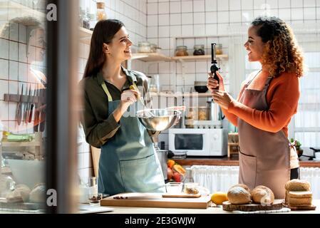 Glückliche zwei Freundinnen schießen Video mit Handy zu Online teilen, während Kochen in der Küche zu Hause Stockfoto