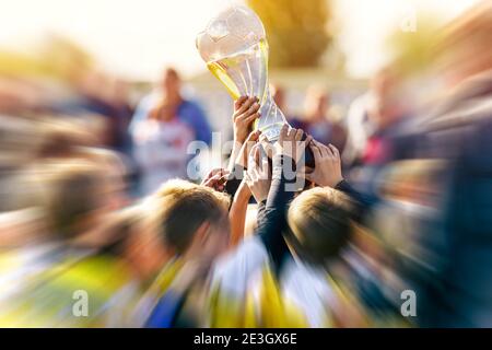 Kinder halten Pokal über Kopf in einem Stadion. Gruppe von glücklichen Jungen steigt goldene Tasse nach dem Gewinn Fußball-Finale Turnierspiel. Kind Stockfoto