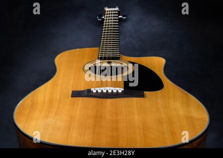 Akustikgitarre mit gelbem Deck und schwarzem Schlagbrett auf isoliert Schwarzer Hintergrund Stockfoto