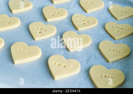 Prozess der Herstellung von herzförmigen Plätzchen mit dem Wort LIEBE bereit zu backen. Konditorei-Konzept. Stockfoto