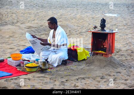 Hindu Priester Zeitung lesen, vor dem Waschen weg Sünden der Pilger, Varkala Beach, Varkala, Kerala, Indien Stockfoto