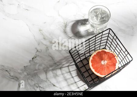 Sommer Schreibwaren Stillleben Szene. Nahaufnahme von geschnittenen Grapefruitfrüchten auf weißem Tischhintergrund im Sonnenlicht. Leere Papierkarten, Einladungen Mockup Szene Stockfoto