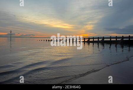 Portobello, Edinburgh, Schottland, Großbritannien. Januar 2021. Bei 2 Grad Celsius guckte die Sonne hinter den Wolken über einen sehr ruhigen Firth of Forth bei Morgendämmerung. Quelle: Arch White/Alamy Live News. Stockfoto