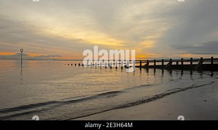 Portobello, Edinburgh, Schottland, Großbritannien. Januar 2021. Bei 2 Grad Celsius guckte die Sonne hinter den Wolken über einen sehr ruhigen Firth of Forth bei Morgendämmerung. Quelle: Arch White/Alamy Live News. Stockfoto