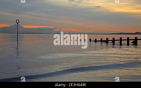 Portobello, Edinburgh, Schottland, Großbritannien. Januar 2021. Bei 2 Grad Celsius guckte die Sonne hinter den Wolken über einen sehr ruhigen Firth of Forth bei Morgendämmerung. Quelle: Arch White/Alamy Live News. Stockfoto