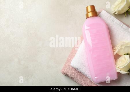 Handtuch, Wäscheflüssigkeit und Rosen auf hellbeige strukturiertem Hintergrund Stockfoto