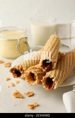 Konzept des Frühstücks mit Waffelrollen mit Kondensmilch auf Weißer strukturierter Hintergrund Stockfoto