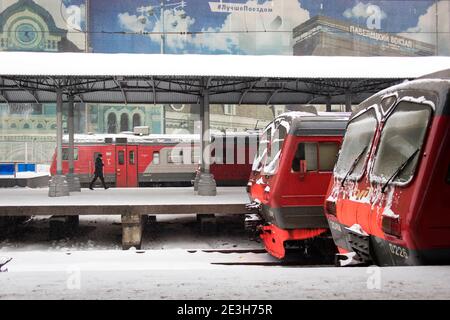 Moskau, Russland - 17. Januar 2021, Region Moskau rote Elektrozüge vor dem Hintergrund der blauen Werbung auf dem Jaroslawski Bahnhof Stockfoto