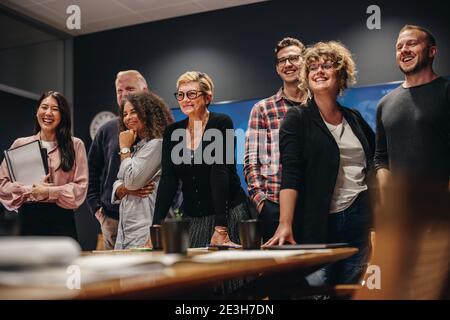 Ein Team aus männlichen und weiblichen Profis steht zusammen. Geschäftsgruppe im Tagungsraum, die für ein Porträt steht. Stockfoto