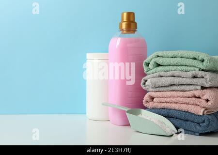 Waschmittel, Schaufel mit Pulver und Handtücher auf weißem Tisch vor blauem Hintergrund Stockfoto