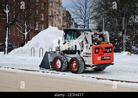 Bobcat S650 Kompaktlader zum Entfernen von Schnee in geparkten an der Seite der Stadtstraße. Helsinki, Finnland. Januar 18, 2021. Stockfoto