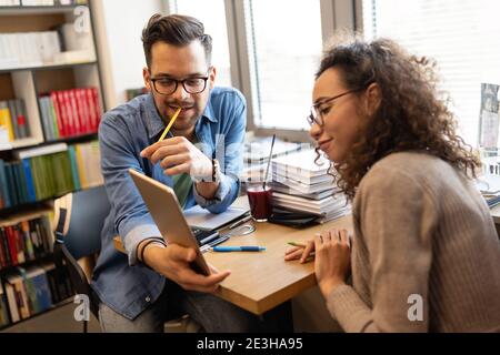 Fröhliche Kollegen, die sich beim Brainstorming im kreativen Büro mit einem Laptop zufrieden geben Stockfoto