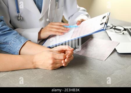 Ärztin, die die Ergebnisse des Elektrokardiogramms mit dem Patienten überprüft Stockfoto