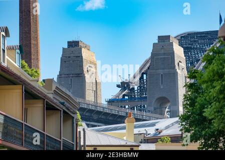 Die südlichen Pylone der Sydney Harbour Bridge sind zu sehen Wachsen aus der Dachlinie der Terrassenhäuser Im historischen The Rocks Viertel in Sydney Stockfoto