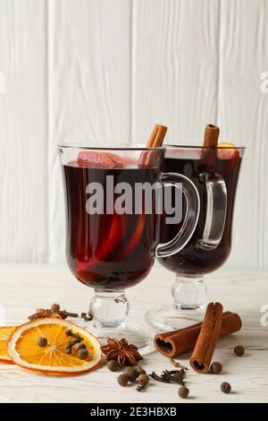 Zwei Gläser dampfenden Glühweins auf einem weißen Holz-Hintergrund, ein helles weihnachtliches Glühwein-Getränk mit Gewürzen und Platz für Text Stockfoto