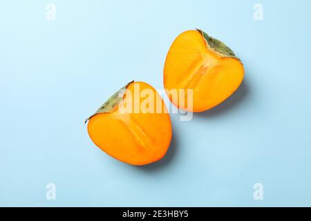 Frische reife Kaki Hälften auf blauem Hintergrund Stockfoto