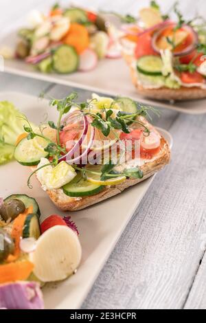 Schnelle und gesunde Rezepte. Salat mit Lachs, Gemüse und Kräutern auf italienischem Ciabatta-Brot. Vertikale Aufnahme Stockfoto