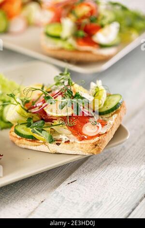 Schnelle und gesunde Lebensmittel Rezepte. Salat mit Lachs, Gemüse und Kräutern auf italienischem Ciabatta-Brot. Mediterrane Gerichte Rezepte. Selektiver Fokus. Vertikale Stockfoto