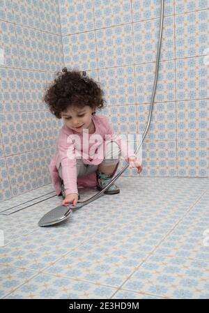 Voll gekleidet, spielt Kleinkind Mädchen in der Dusche Stockfoto