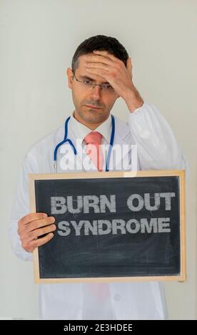 Burn-out-Syndrom im Gesundheitswesen persönliches Konzept. Depressiver Arzt zeigt einen Schiefer mit Burnout-Syndrom darauf geschrieben. Stockfoto