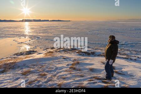 Besucher genießen einen Sonnenuntergang. Winter am Ilulissat Eisfjord, in der Disko Bay in Westgrönland gelegen, ist der Eisfjord Teil des UNESCO-Welterbes Stockfoto