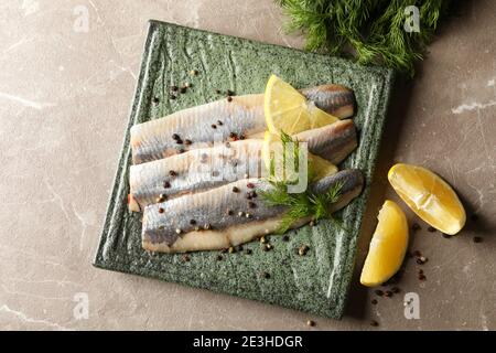 Teller mit Fischscheiben und Gewürzen auf grauem Hintergrund Stockfoto