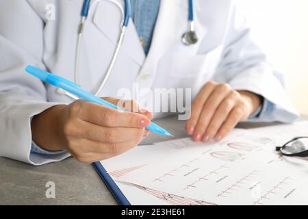 Junge Ärztin im medizinischen Kleid Überprüfung Elektrokardiogramm Ergebnisse Stockfoto