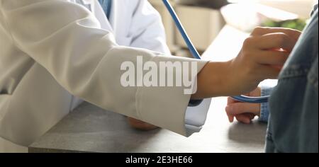 Junge Ärztin im medizinischen Kleid Überprüfung Herzschlag Stockfoto