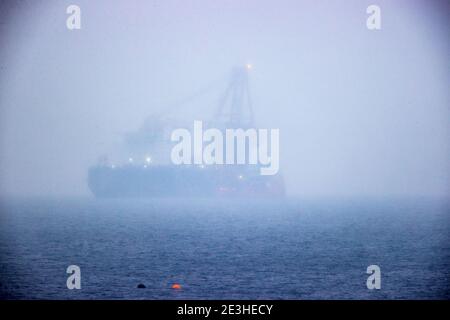 Nienhagen, Deutschland. Januar 2021. Das russische Rohrverlegungsschiff "Fortuna" ist in der Ostsee vor dem Hafen von Rostock verankert, kaum sichtbar im Nebel und Schneeregen. Das Spezialschiff soll für Bauarbeiten an der deutsch-russischen Nord Stream 2 Ostsee-Gaspipeline eingesetzt werden. Die USA wollen erstmals Sanktionen gegen die Gaspipeline verhängen. Die Strafmaßnahmen betreffen das russische Laienschiff "Fortuna", das am Bau der Pipeline beteiligt ist. Quelle: Jens Büttner/dpa-Zentralbild/dpa/Alamy Live News Stockfoto