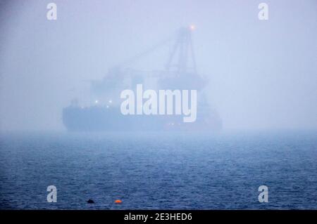 Nienhagen, Deutschland. Januar 2021. Das russische Rohrverlegungsschiff "Fortuna" ist in der Ostsee vor dem Hafen von Rostock verankert, kaum sichtbar im Nebel und Schneeregen. Das Spezialschiff soll für Bauarbeiten an der deutsch-russischen Nord Stream 2 Ostsee-Gaspipeline eingesetzt werden. Die USA wollen erstmals Sanktionen gegen die Gaspipeline verhängen. Die Strafmaßnahmen betreffen das russische Laienschiff "Fortuna", das am Bau der Pipeline beteiligt ist. Quelle: Jens Büttner/dpa-Zentralbild/dpa/Alamy Live News Stockfoto