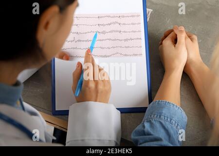 Ärztin, die die Ergebnisse des Elektrokardiogramms mit dem Patienten überprüft Stockfoto