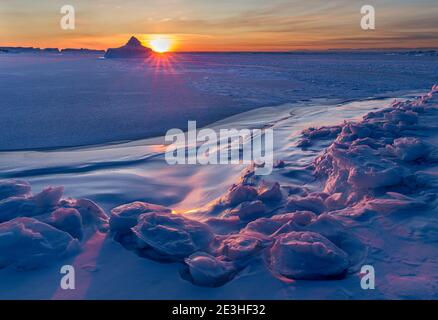 Sonnenuntergang am Ufer der gefrorenen Disko Bay. Disko Bay im Winter, Westgrönland. Amerika, Nordamerika, Grönland, Dänemark Stockfoto