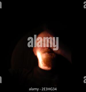 Porträt des mans Kopf durch Fackelschein auf schwarzem Hintergrund beleuchtet Stockfoto