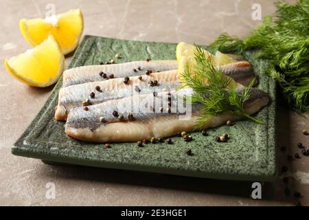 Teller mit Fischscheiben und Gewürzen auf grauem Hintergrund Stockfoto