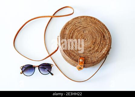 Boho Stil, runde ATA Rattan Tasche mit einem Leder Schultergurt und Sonnenbrille, isoliert auf weißem Hintergrund Stockfoto