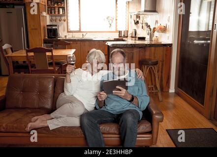 Glückliche aktive ältere Mann und Frau Video-Anrufe Familie mit digitalen Tablet. Paare genießen zusammen Streaming-Film oder Nachrichten im Internet auf Stockfoto