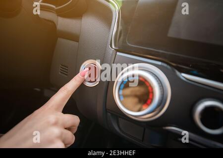 Der Finger der Frau drückt während der Fahrt auf die Notlichtaster. Detail auf dem Armaturenbrett des Autos. Stockfoto
